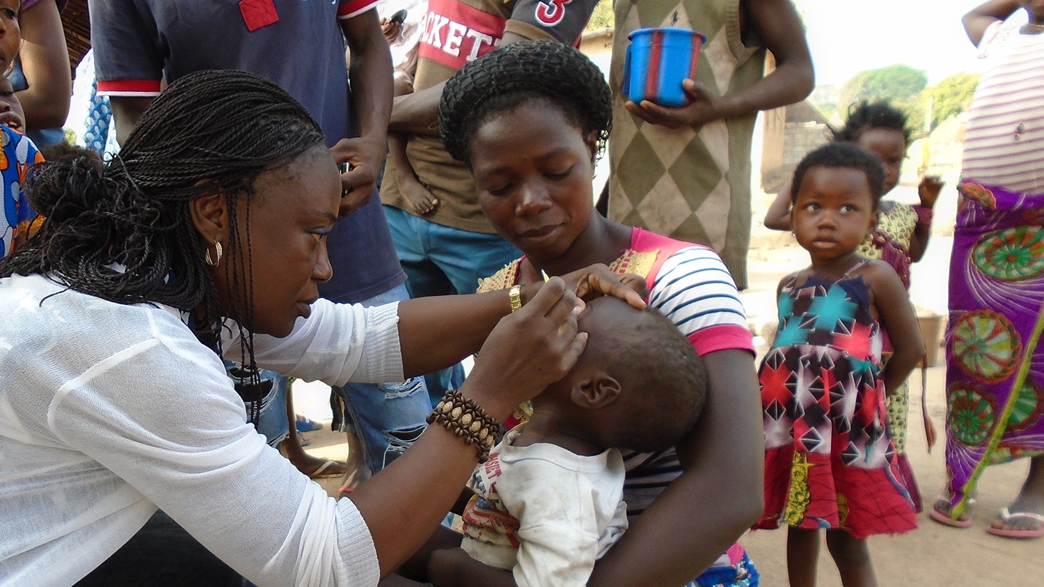 An eye health worker checks a toddler's eyes for trachoma during a community screening.