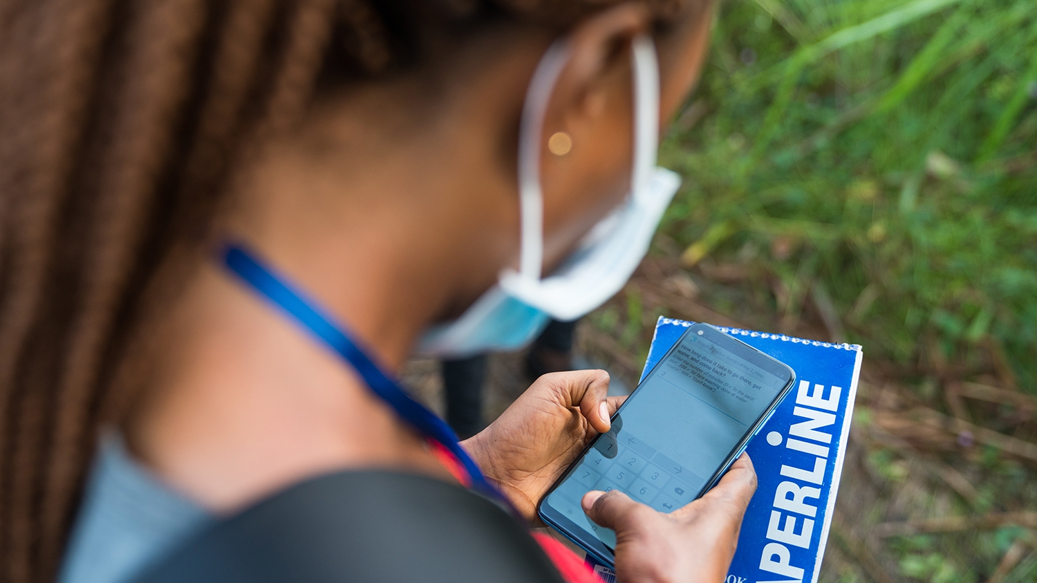 A female researcher uses a mobile phone to survey a community for trachoma in Sierra Leone.