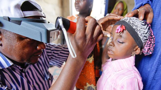 A health worker checks a girl's eyes