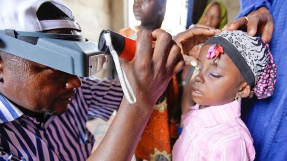 A young girl gets her eyes checked by a health worker