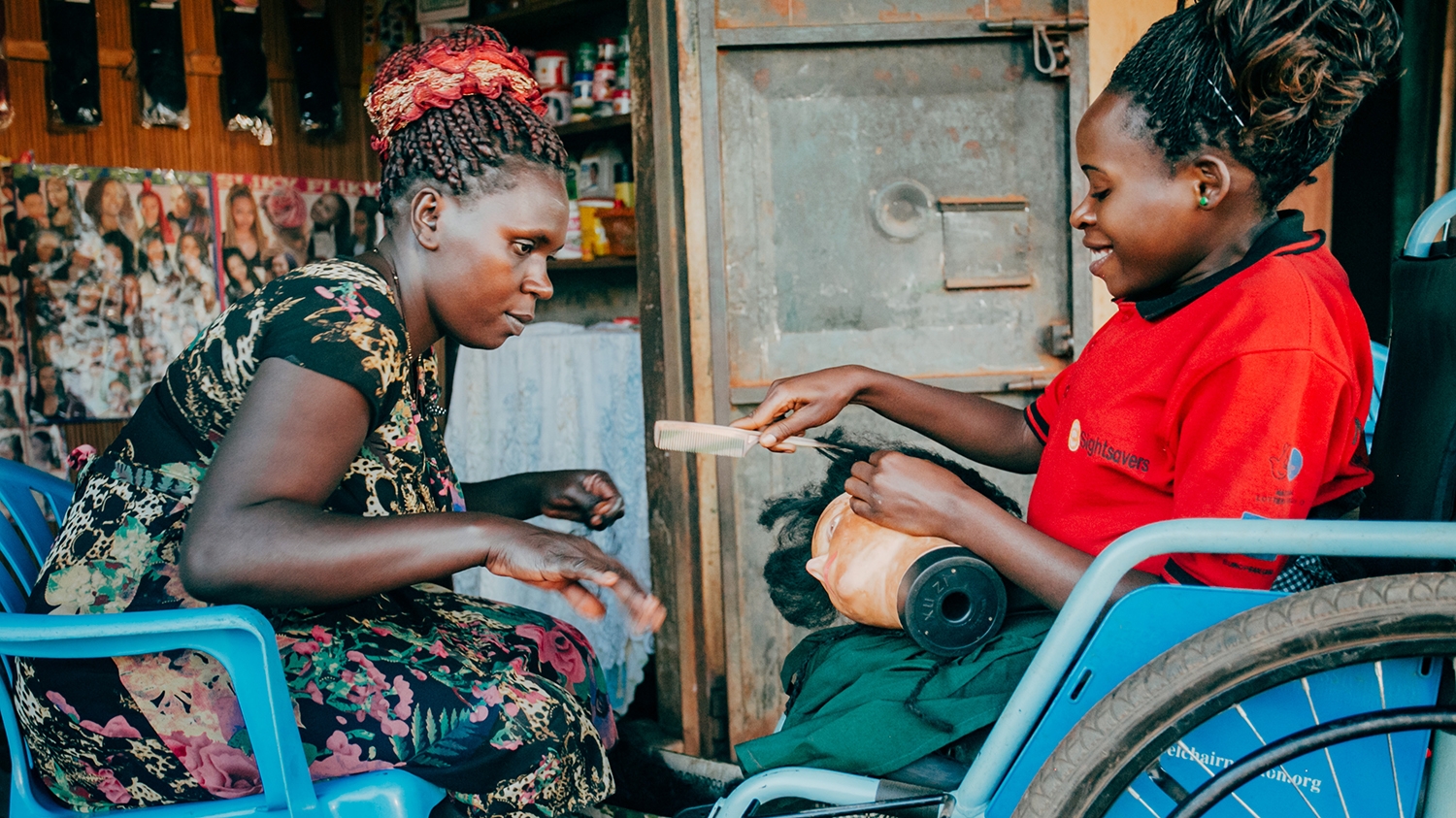 Beatrice trains intern Irene, who uses a wheelchair, at a hair salon in Uganda.