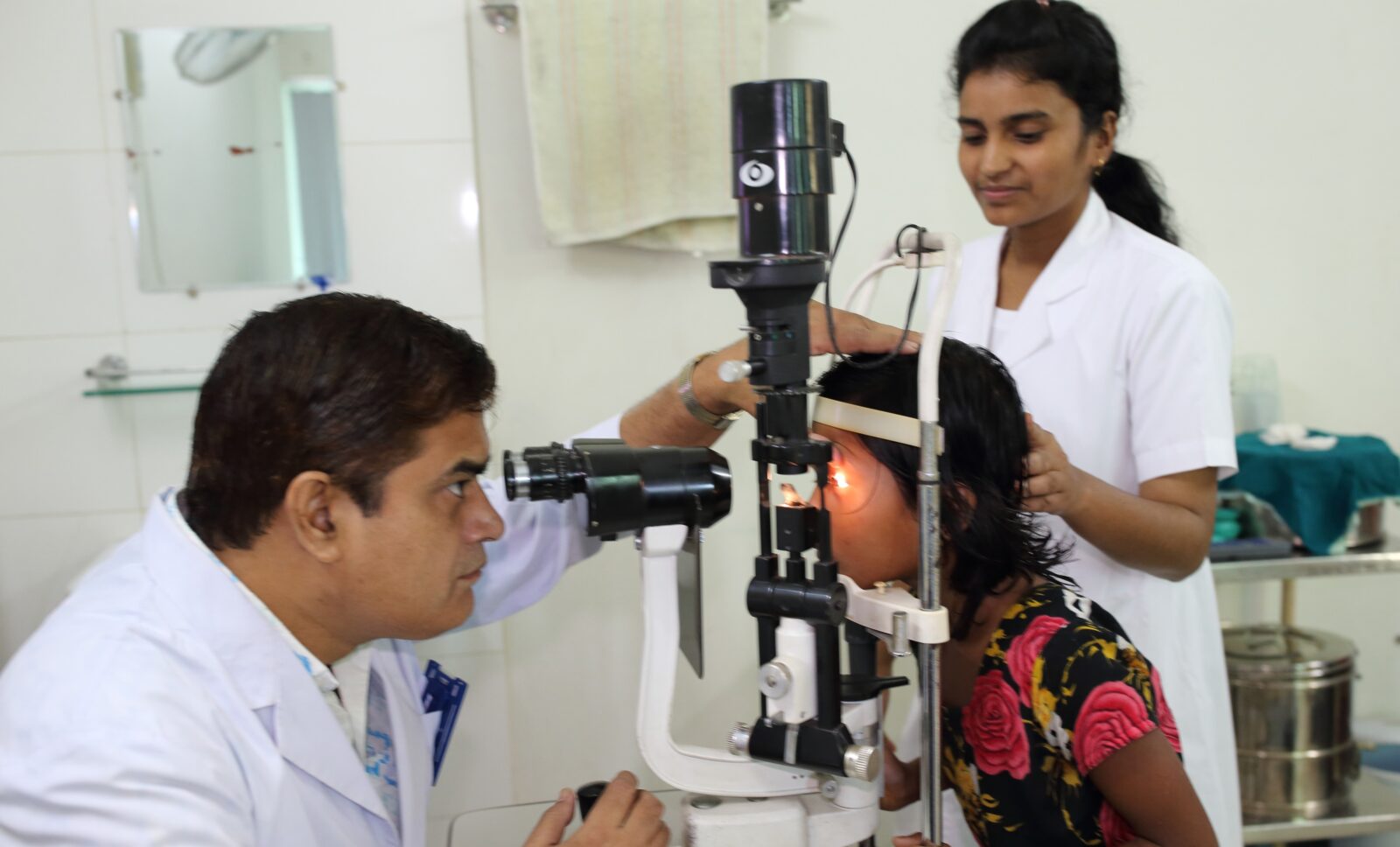 a doctor uses a piece of medical equipment to check a young female patient's eyes