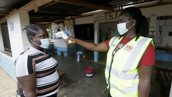 A health worker tests a patient's temperature to check for COVID-19, using a digital thermometer.