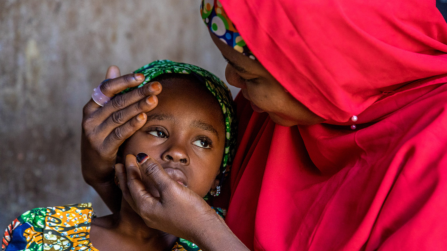 A young girl with cataracts is comforted by her mother.