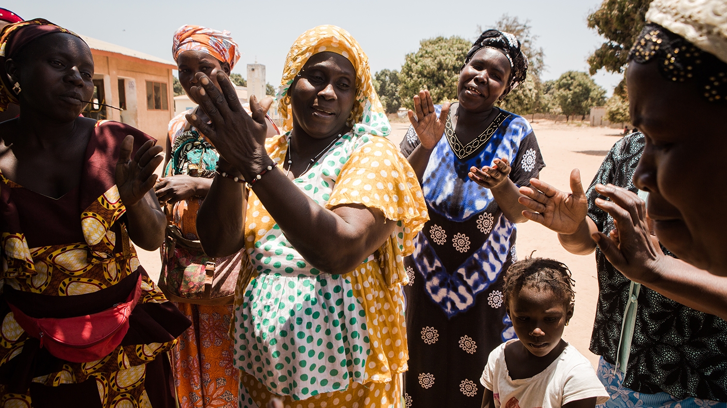 A group of women and children sing and dance during a trachoma awareness session in The Gambia.