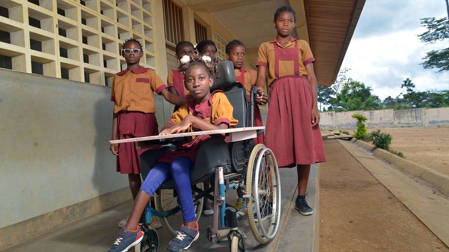 Lesline, who uses a wheelchair, outside classroom with other pupils.