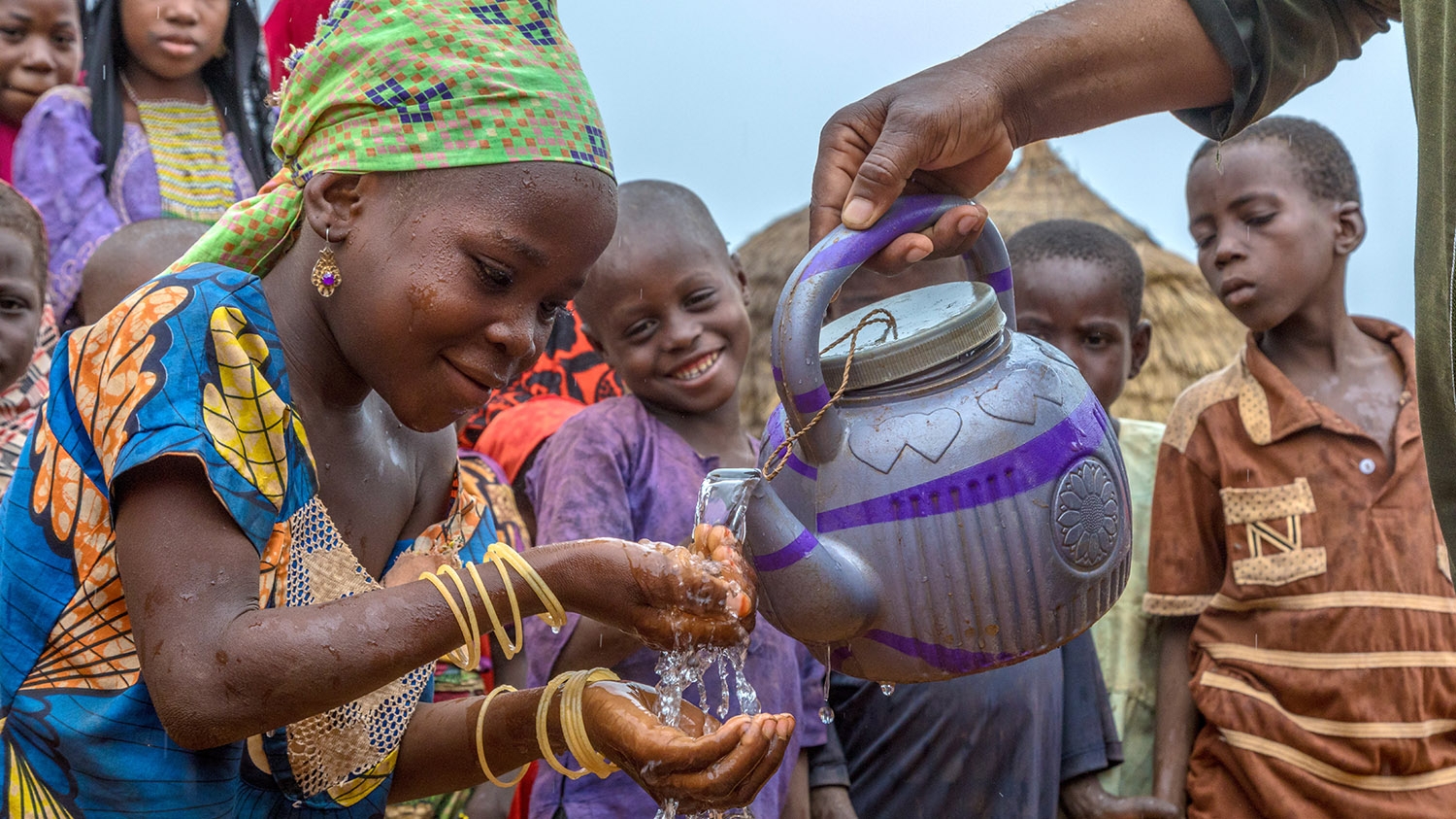 A young girl washes her hands using water poured from a teapot during a social behaviour change session in Nigeria.