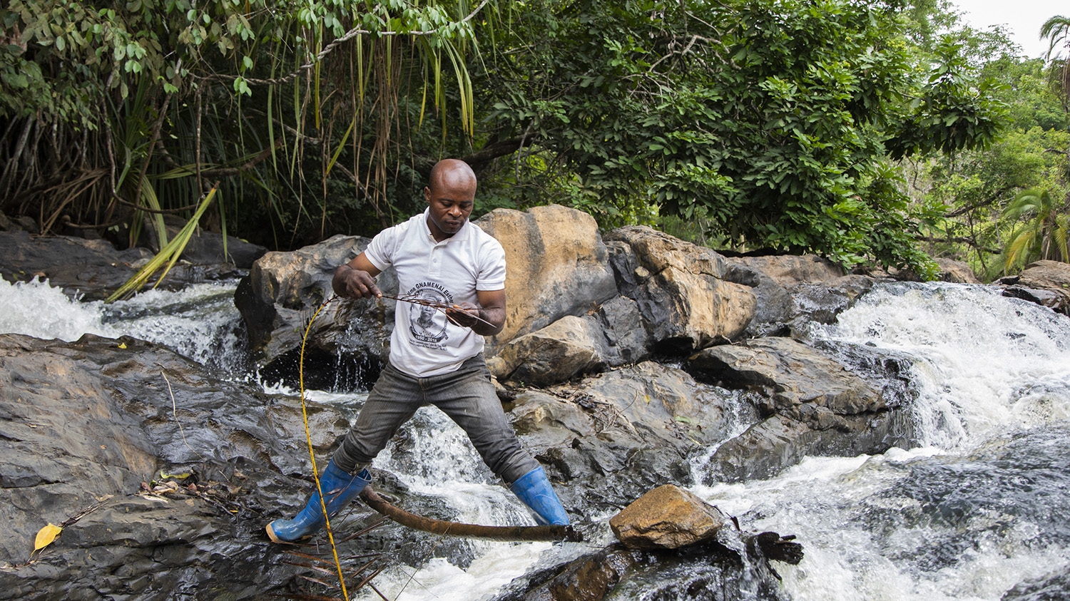 Entomologist Nijikan Soule stands precariously on the banks of a river in Ethiopia while prospecting for fly larvae.