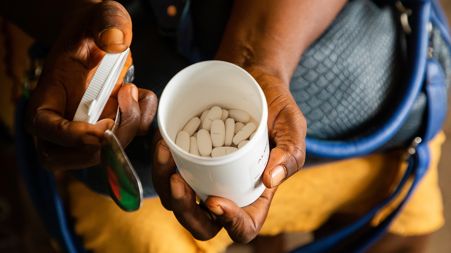 A close-up of a volunteer's hands holding medication that treats intestinal worms.