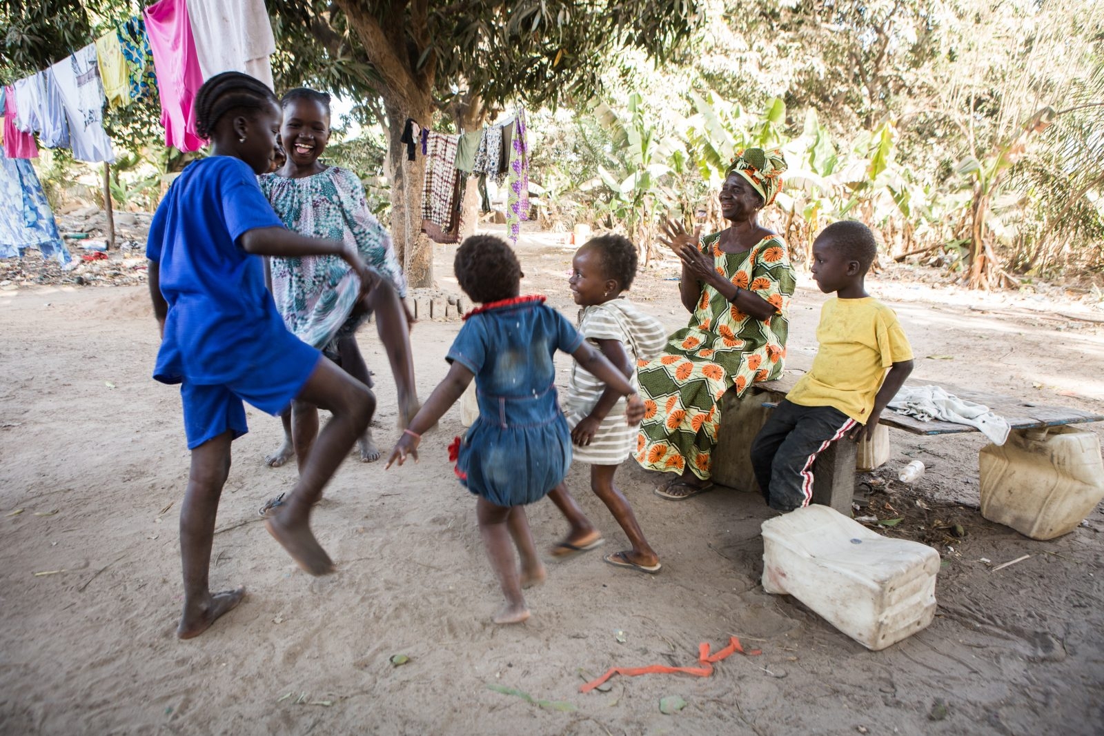 A group of young children laugh and dance in celebration of trachoma elimination.