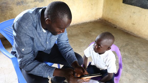 A teacher in Kenya assesses a young child's learning development.